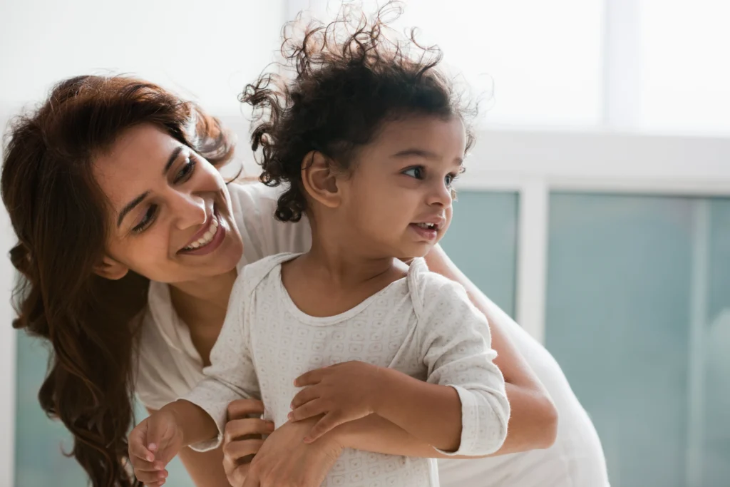 A woman and a child smile while embracing each other, conveying warmth and affection in a joyful moment.